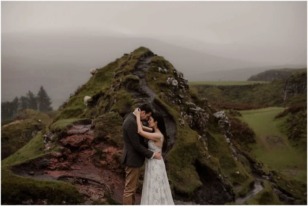 Couple holding each other close on the rocky mounds of Fairy Glen, Isle of Skye, on a rainy autumn morning