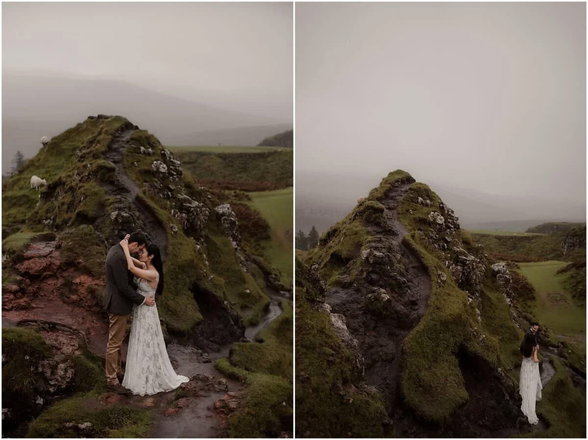 Couple embracing beside the iconic mossy rock formation at Fairy Glen, Isle of Skye, with sheep grazing on the hillside behind them in the mist