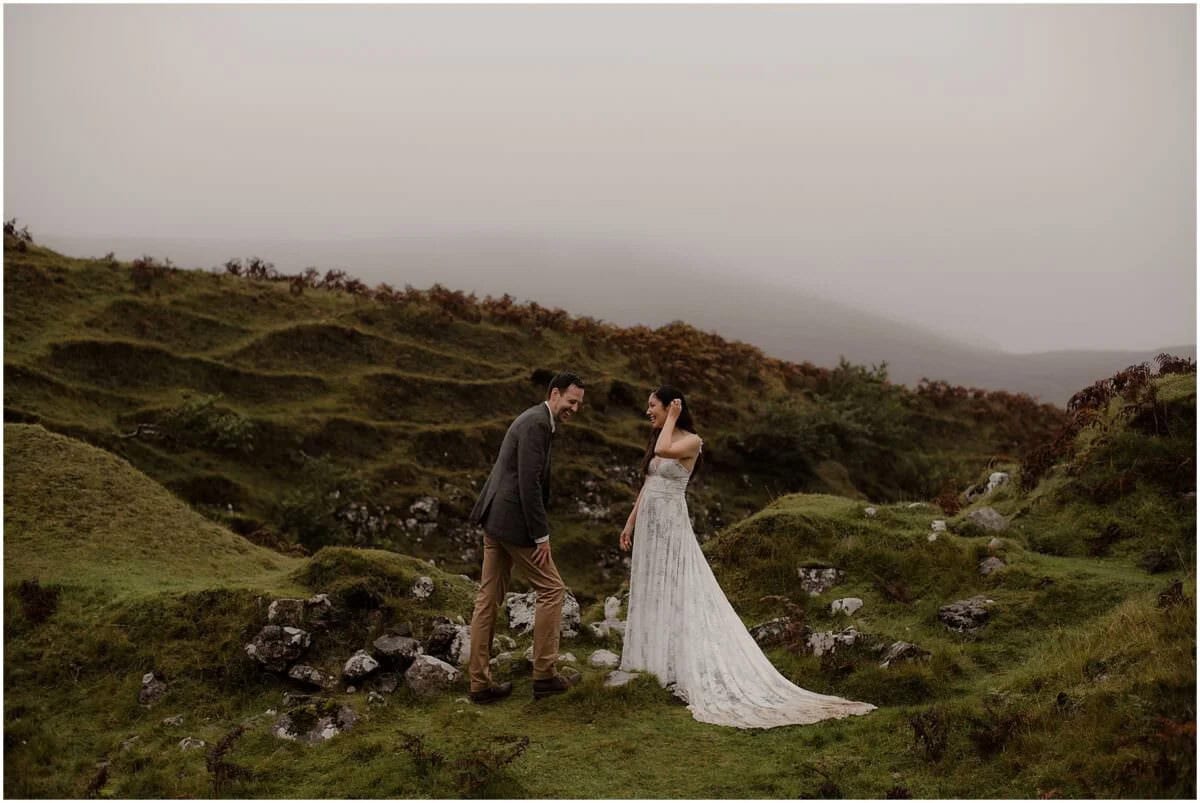 Couple laughing together while walking through the rolling green mounds of Fairy Glen, Isle of Skye, on a misty autumn morning