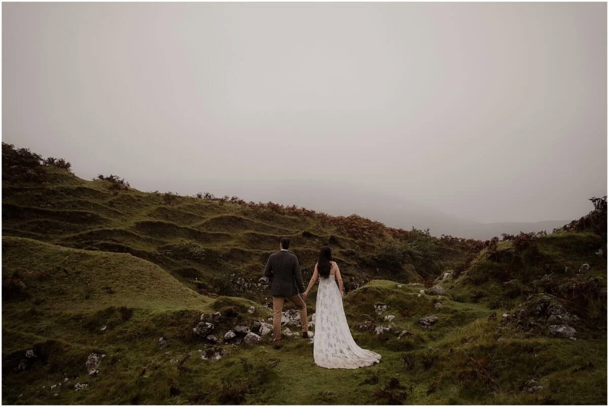 Couple walking hand in hand away from the camera through Fairy Glen