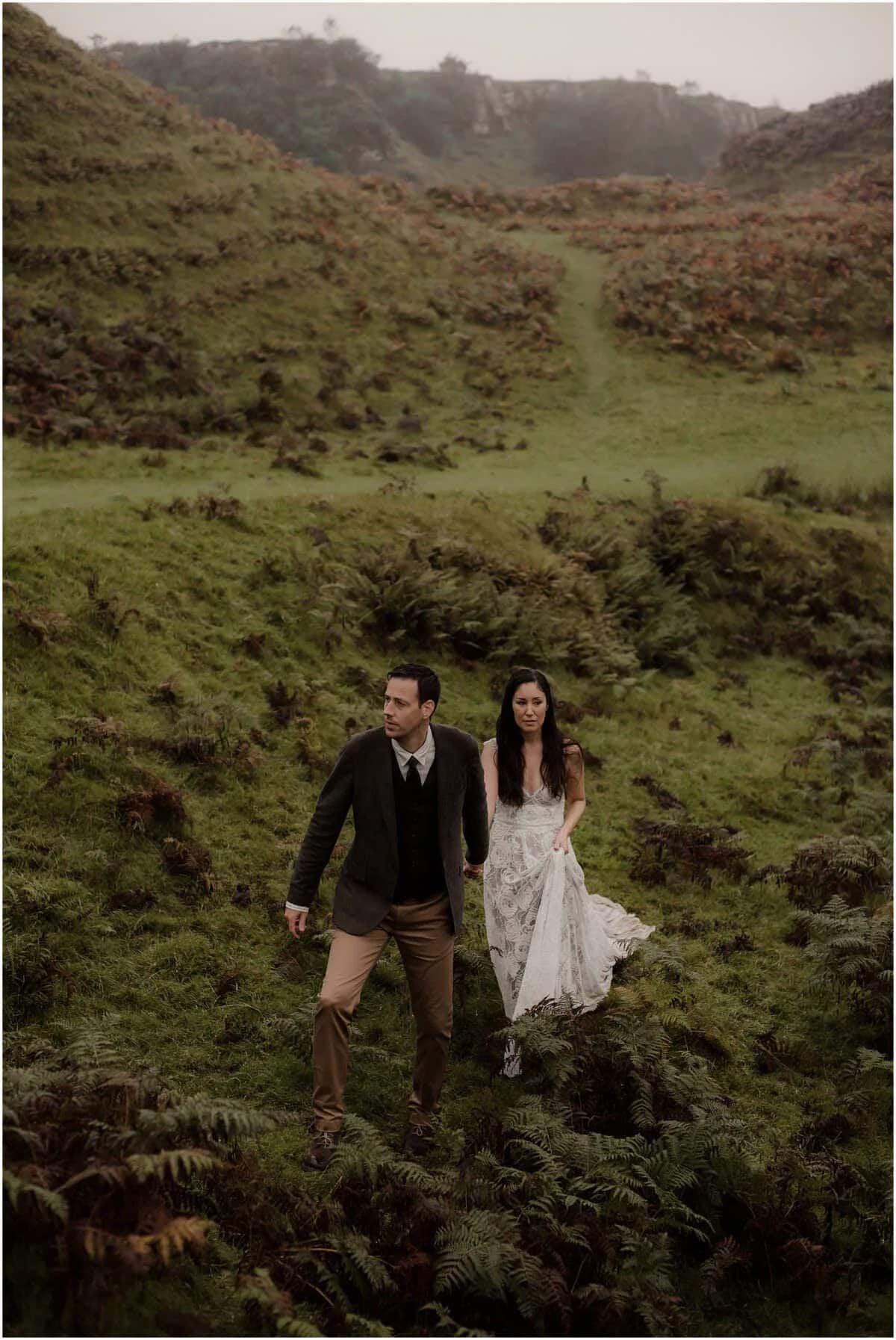 Couple walking through the fern-filled valley at Fairy Glen, Isle of Skye, on an overcast autumn day