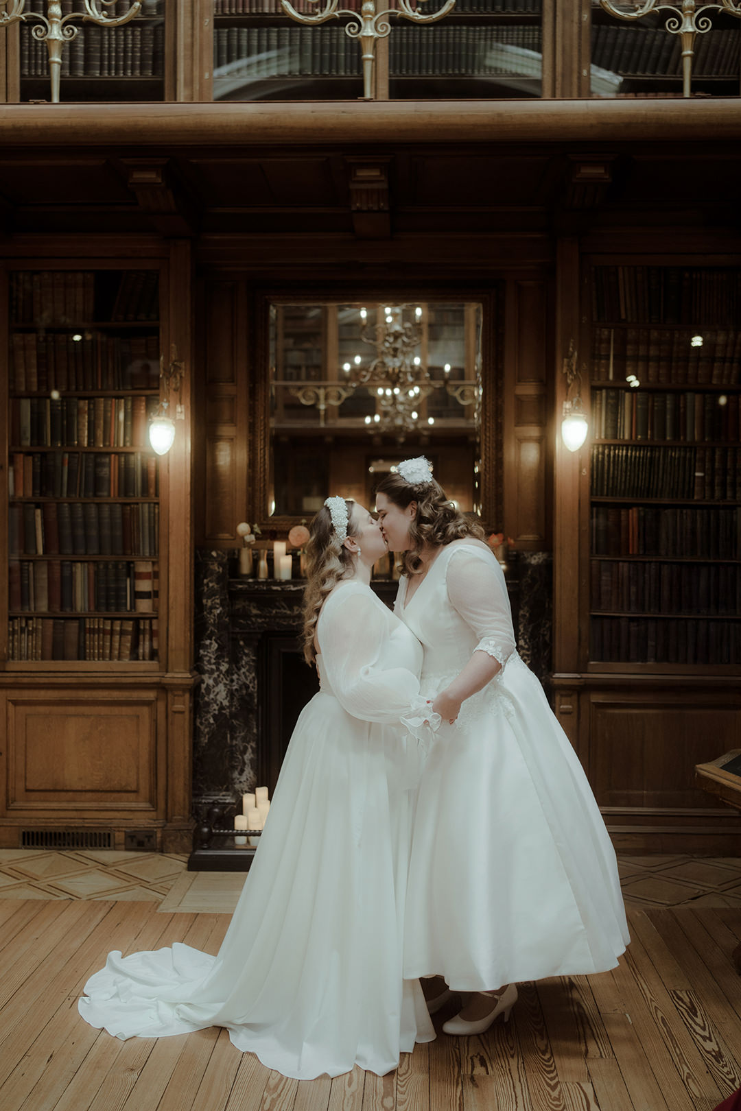 Lesbian couple share a kiss during an intimate library elopement ceremony surrounded by antique bookshelves in Edinburgh, Scotland at their LGBTQ wedding at the Royal College of Physicians