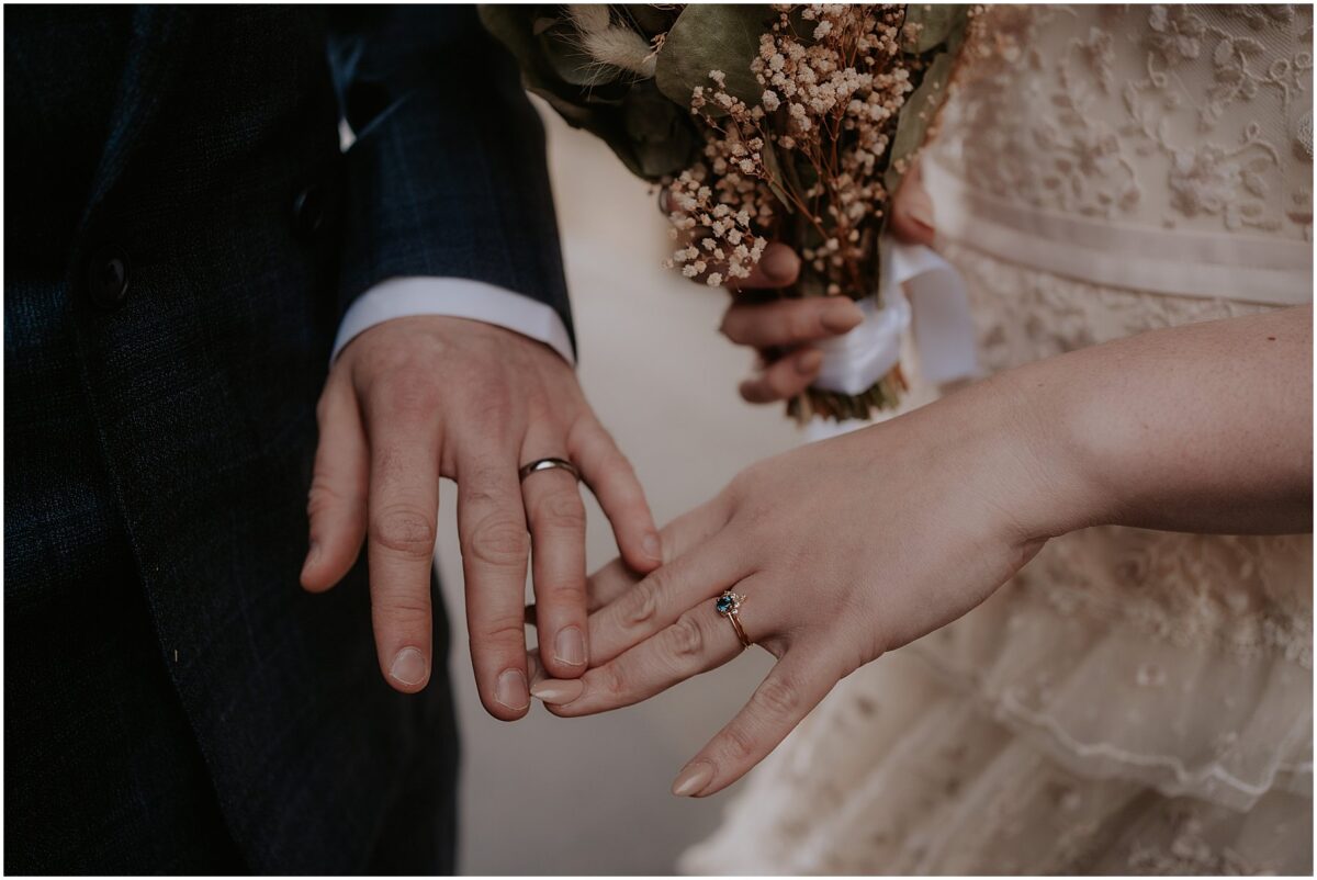 Bride and groom holding hands together showing off their wedding rings