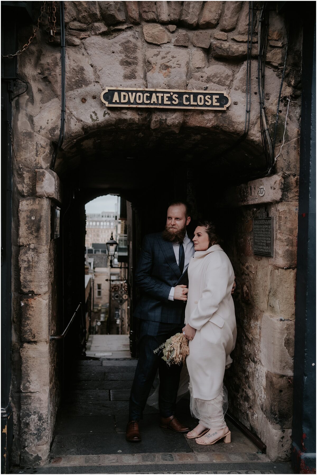 Windy post-ceremony photoshoot on Royal Mile - elegant newlyweds standing close on their windy wedding day