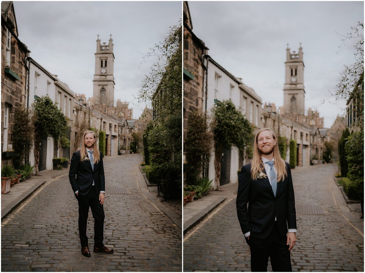 Groom dressed in a navy suit and a blue tie standing in the middle of Edinburgh street with one hand in his pocket