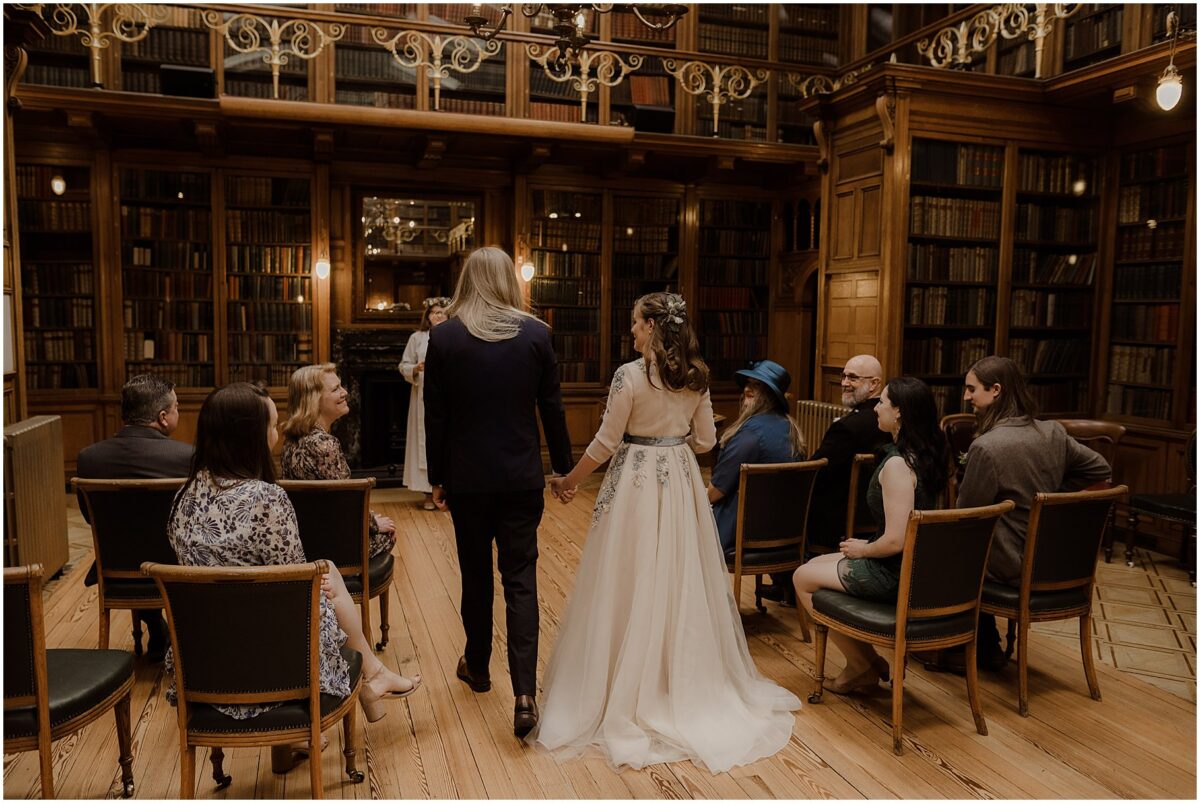 Bride and groom walking down the aisle with guests watching them and smiling softly