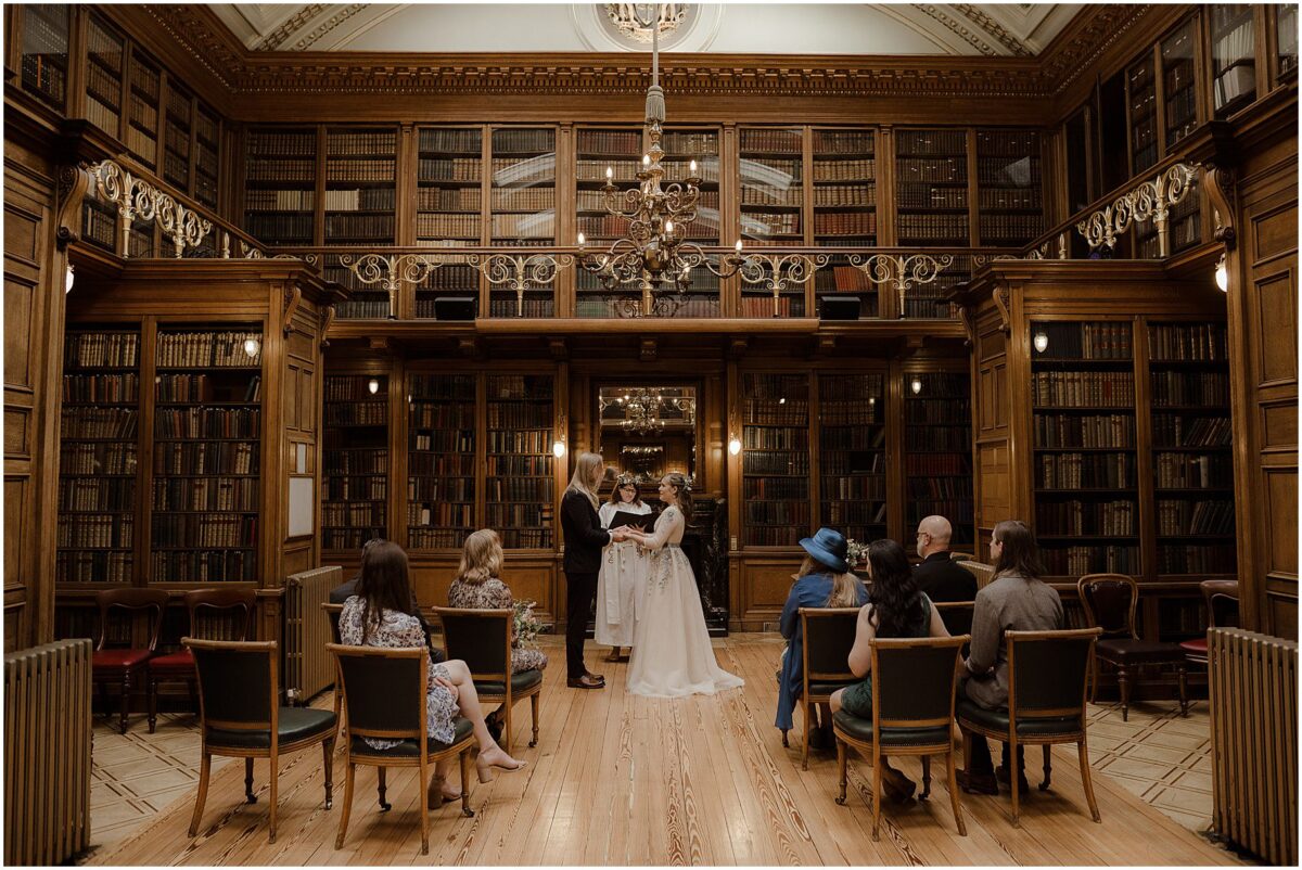 Wide-angle view at the venue with prominent floor-to-ceiling bookshelves and a marble fireplace - Royal College of Physicians Wedding Photos