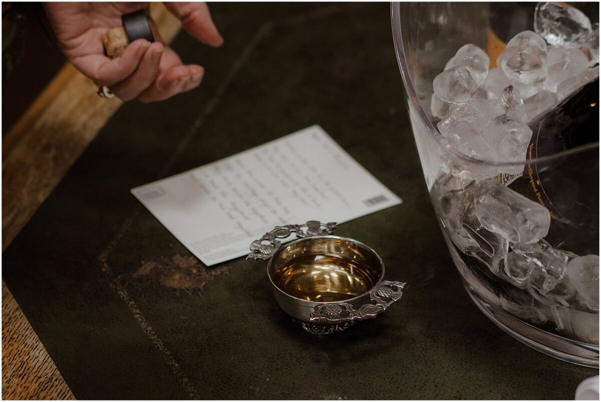 Scottish quaich filled with whisky next to a card with a hand-written reading