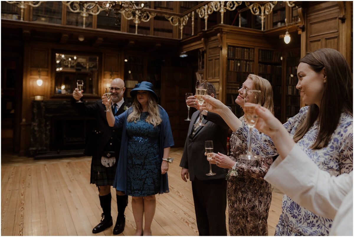 Wedding guests raising their champagne-filled glasses to the married couple