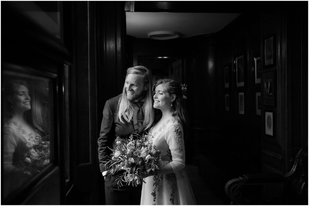 Married couple peaking out the venue window, smiling