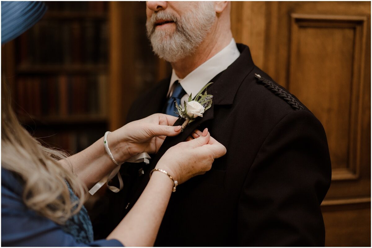 Mother of the bride pinning a boutonniere on the suit jacket of father of the bride