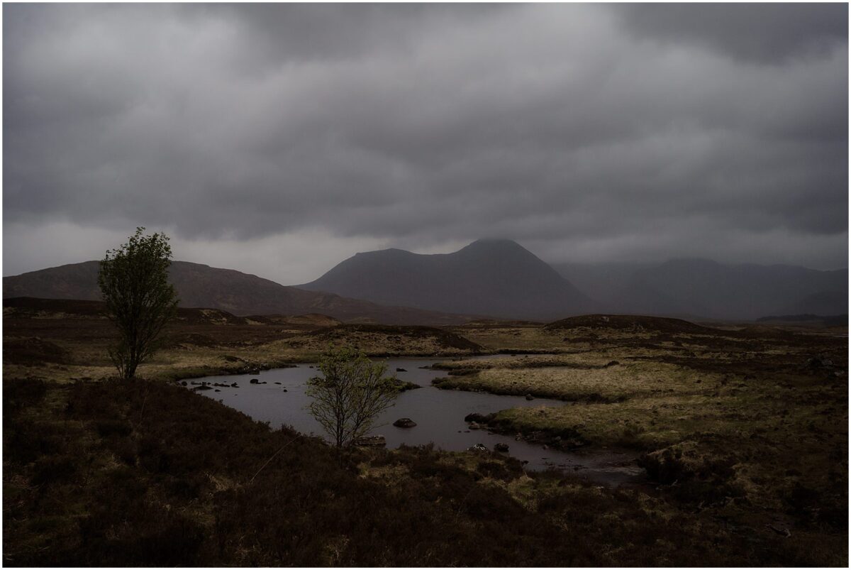 A lone upland lochan sits amidst windswept heather and boggy moor