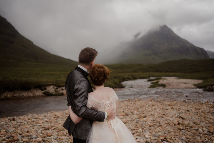 Newlyweds posing with mountain background of the Scottish highlands