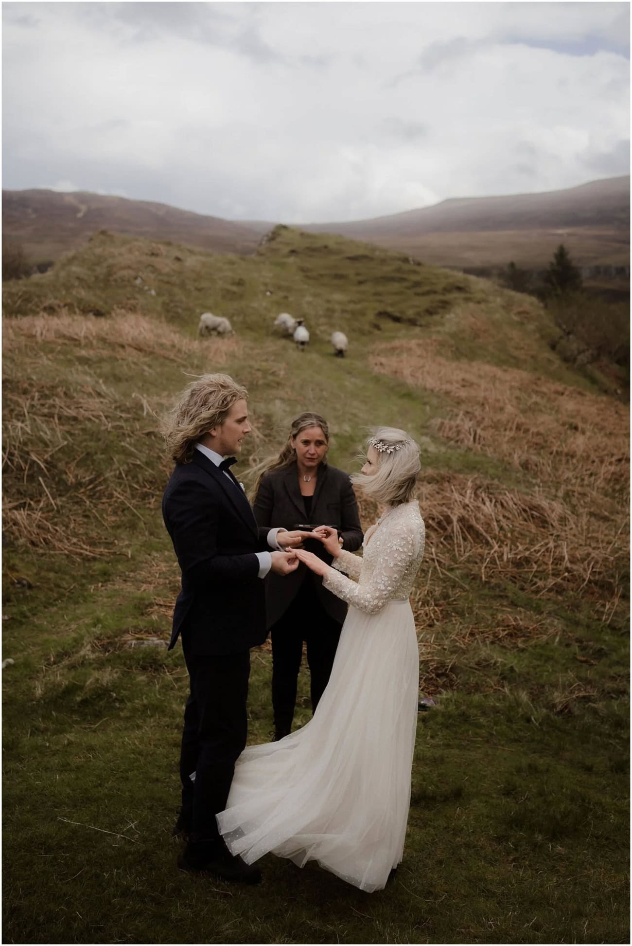 Isle of Skye elopement in Fairy Glen - Isle of Skye wedding photographer Couple exchanging rings during their outdoor elopement ceremony at Fairy Glen, Isle of Skye, with sheep grazing on the hillside behind them