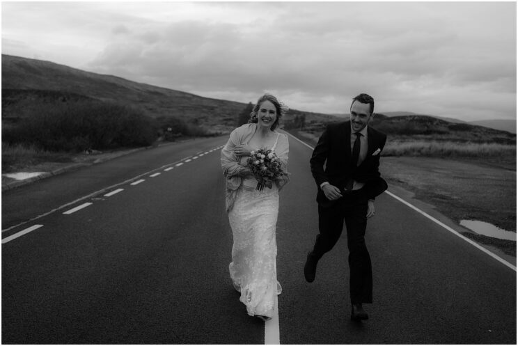Bride and groom running on the road in the Scottish highlands