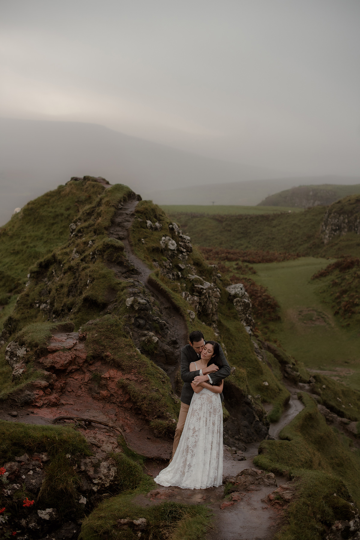 Best Time to Elope in Scotland: A Season-by-Season Guide 43 Autumn elopement at Fairy Glen, Isle of Skye, with bride and groom hugging on a narrow moss-covered ridge in moody, foggy Highland weather