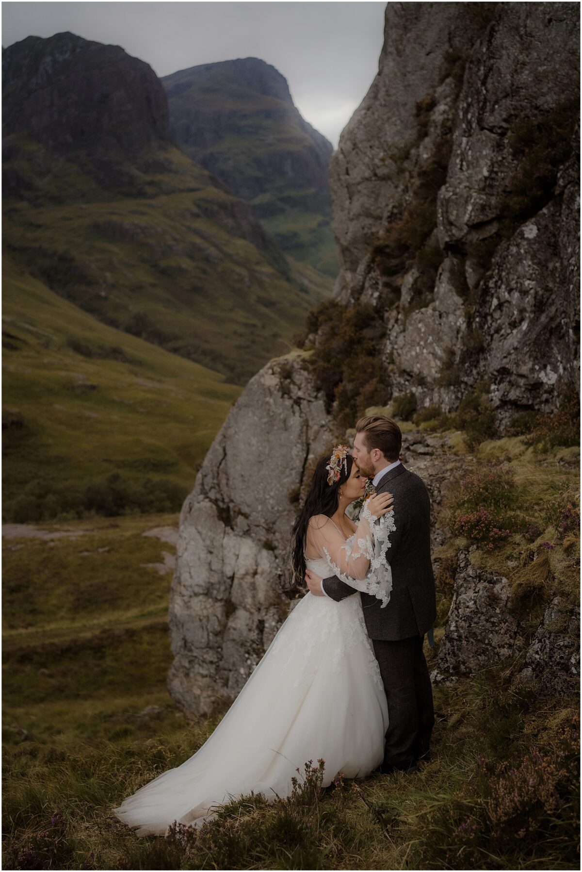 Wedding photos in Glencoe - Glencoe wedding photographer Groom giving the bride a kiss on the forehead whilst embracing her, her lacy sleeves stretching around him