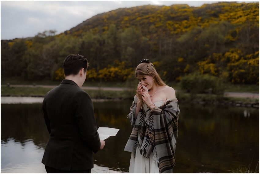 Two brides exchanging vows and laughing at their outdoor LGBT wedding in Holyrood Park in Scotland