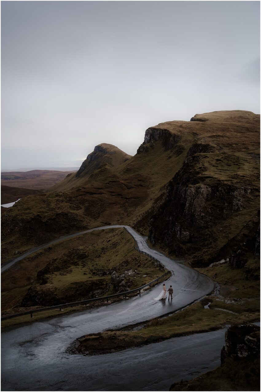 Newlyweds walking on the Quiraing road holding hands after their Scotland elopement ceremony