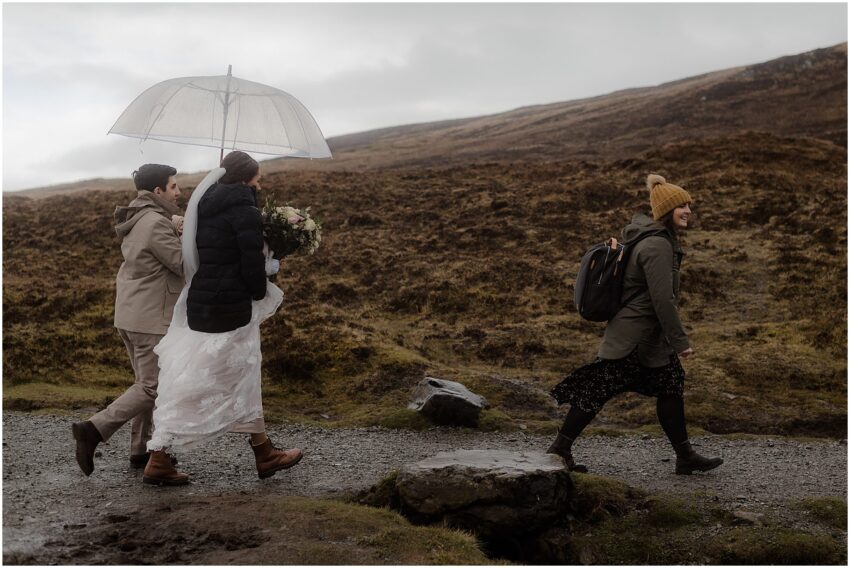 Bride, groom and their humanist celebrant walking to the elopement ceremony location in Quiraing, Scottish highlands