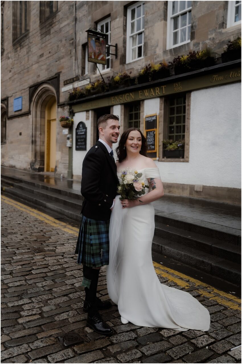 Newlyweds standing in front of a pub on Royal Mile - Edinburgh wedding photos