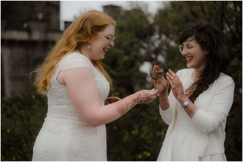 Two brides sharing a goblet filled with wine together