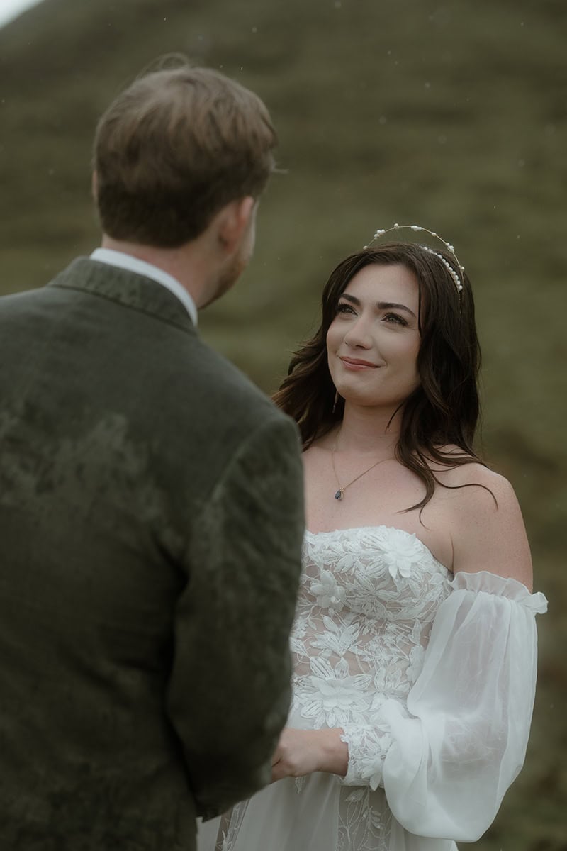 Isle of Skye Elopement Guide 2026/27 – plan your Scottish adventure wedding 3 Close-up of a bride tearing up and smiling at her groom during their elopement ceremony at the Quiraing, Isle of Skye, rain visible in the air around her
