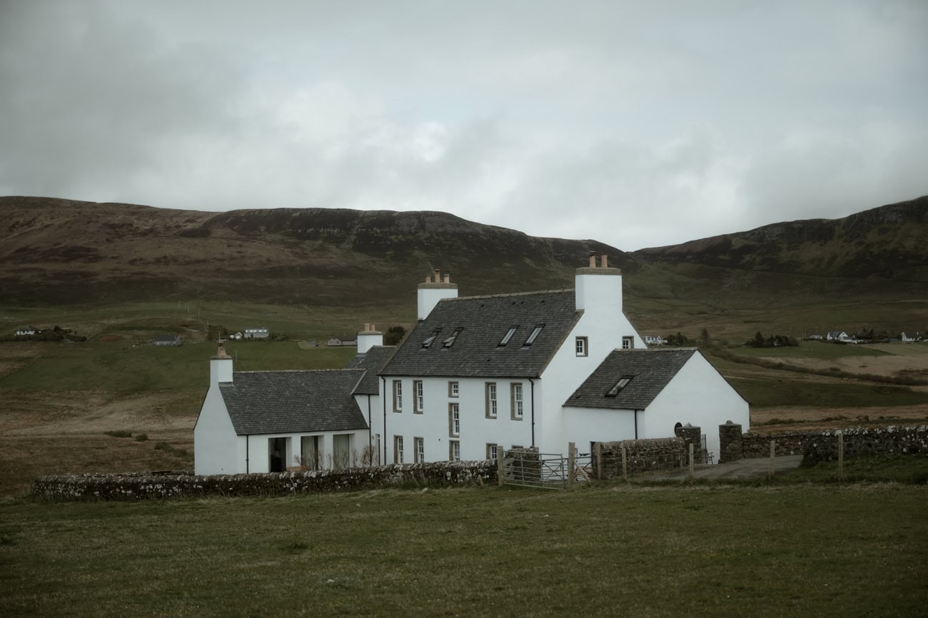 Isle of Skye Elopement Guide 2026/27 – plan your Scottish adventure wedding 25 Monkstadt 1745 hotel on the Isle of Skye, a whitewashed historic farmhouse surrounded by open moorland and rolling hills under an overcast sky