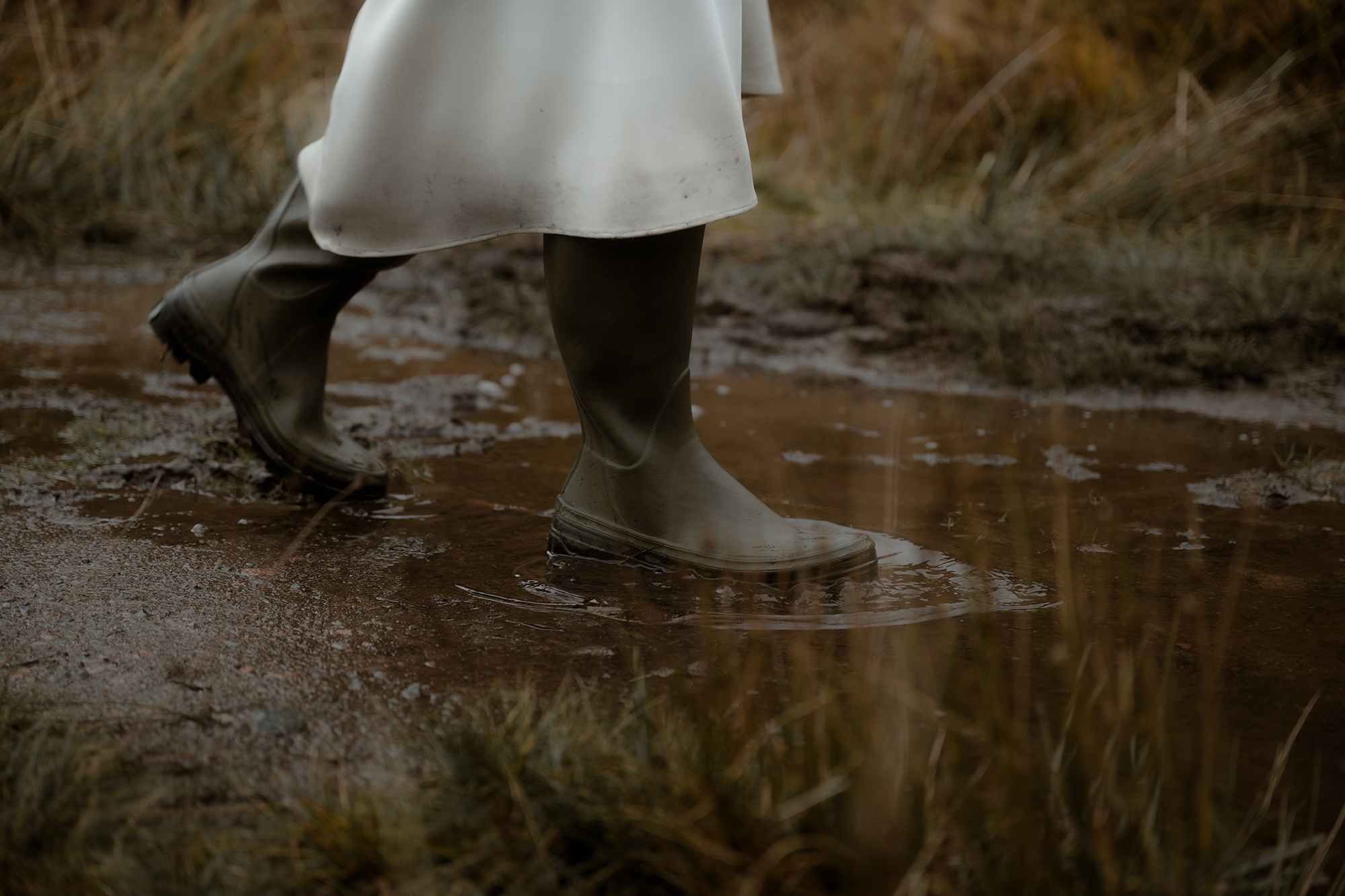 Advice for Rainy Wedding Days in Scotland - turn rain into romance 7 Close-up of bride's rubber boots whilst she's going through puddles in her wedding dress