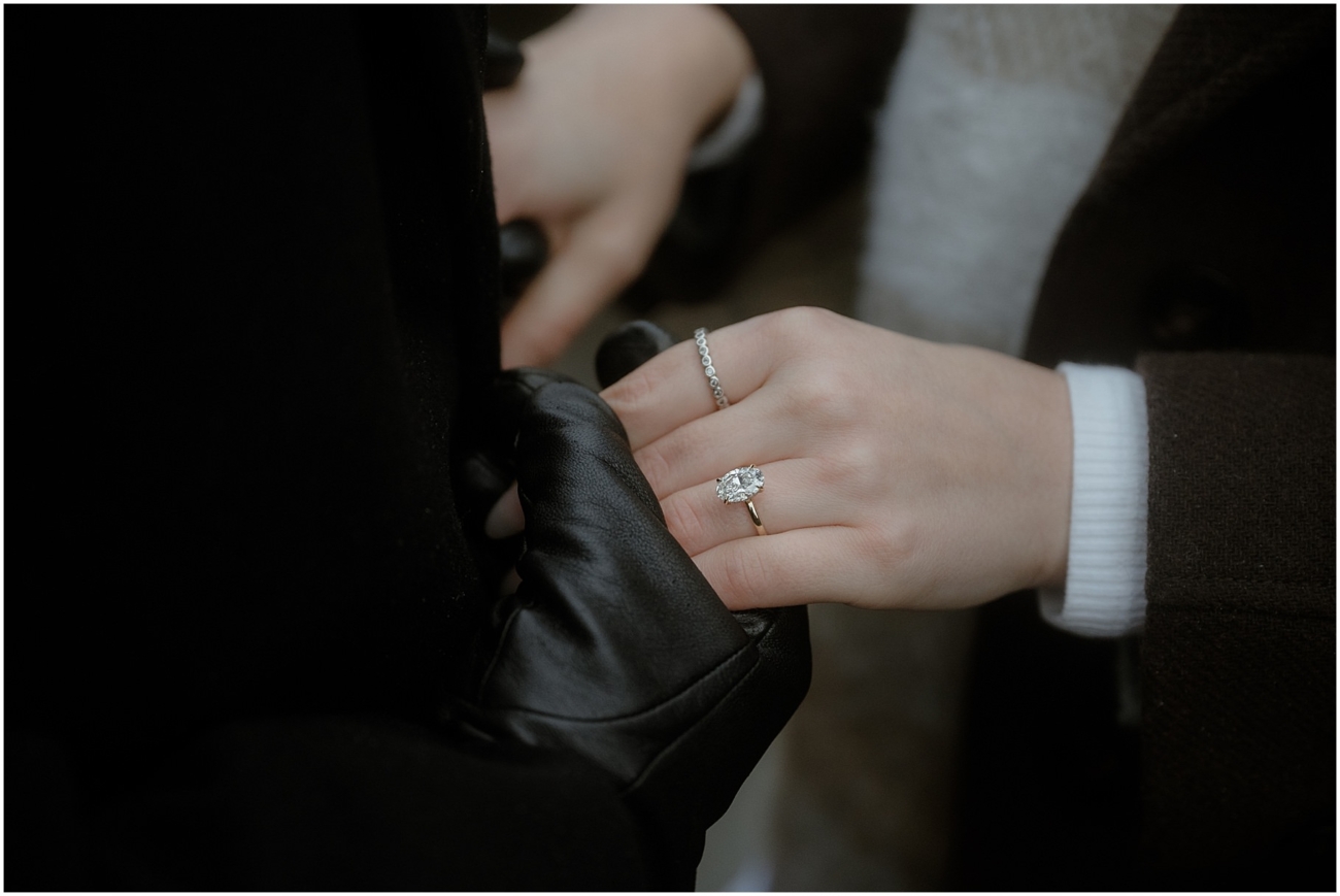 A close-up shot of the engagement ring on the woman’s hand, featuring a stunning oval-cut diamond