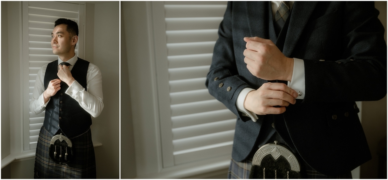 The groom, dressed in a traditional dark Scottish kilt, adjusts his cufflinks and tie while getting ready for the wedding ceremony