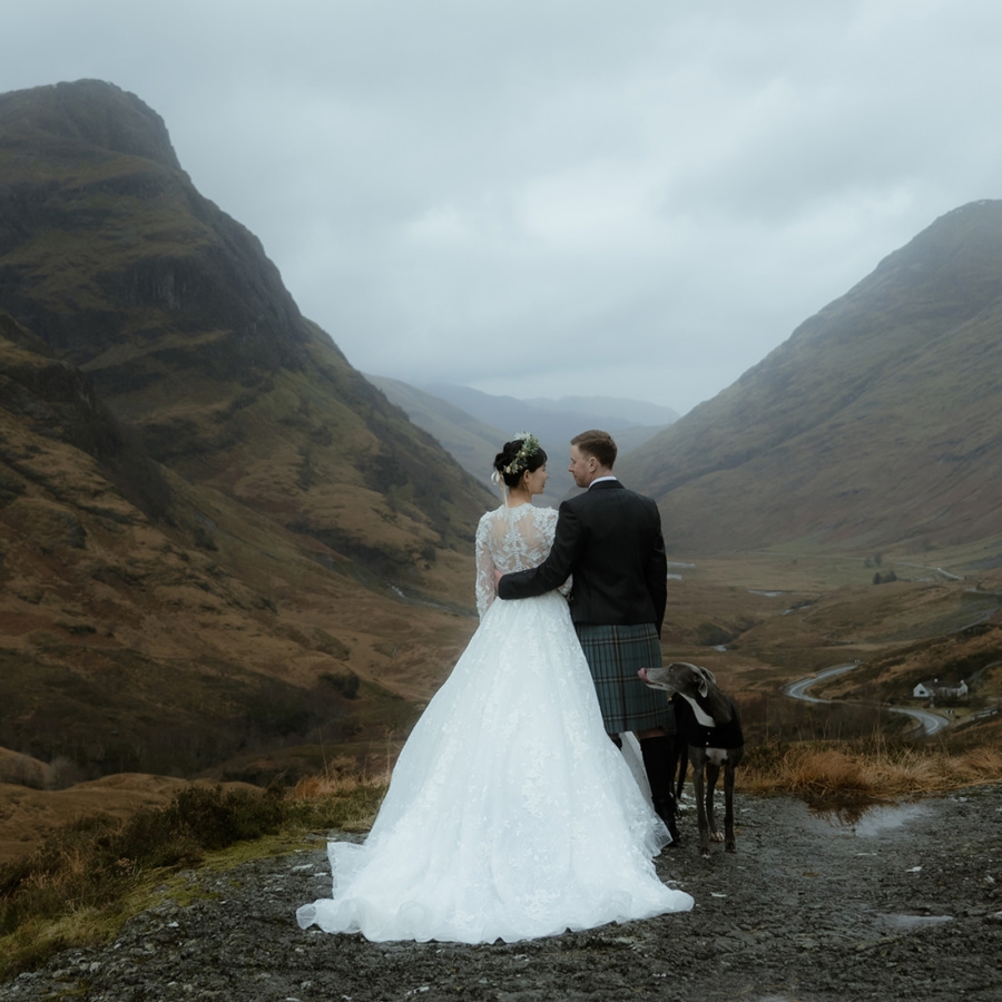 Bride and groom embracing at their Scottish wedding with greyhound by their side