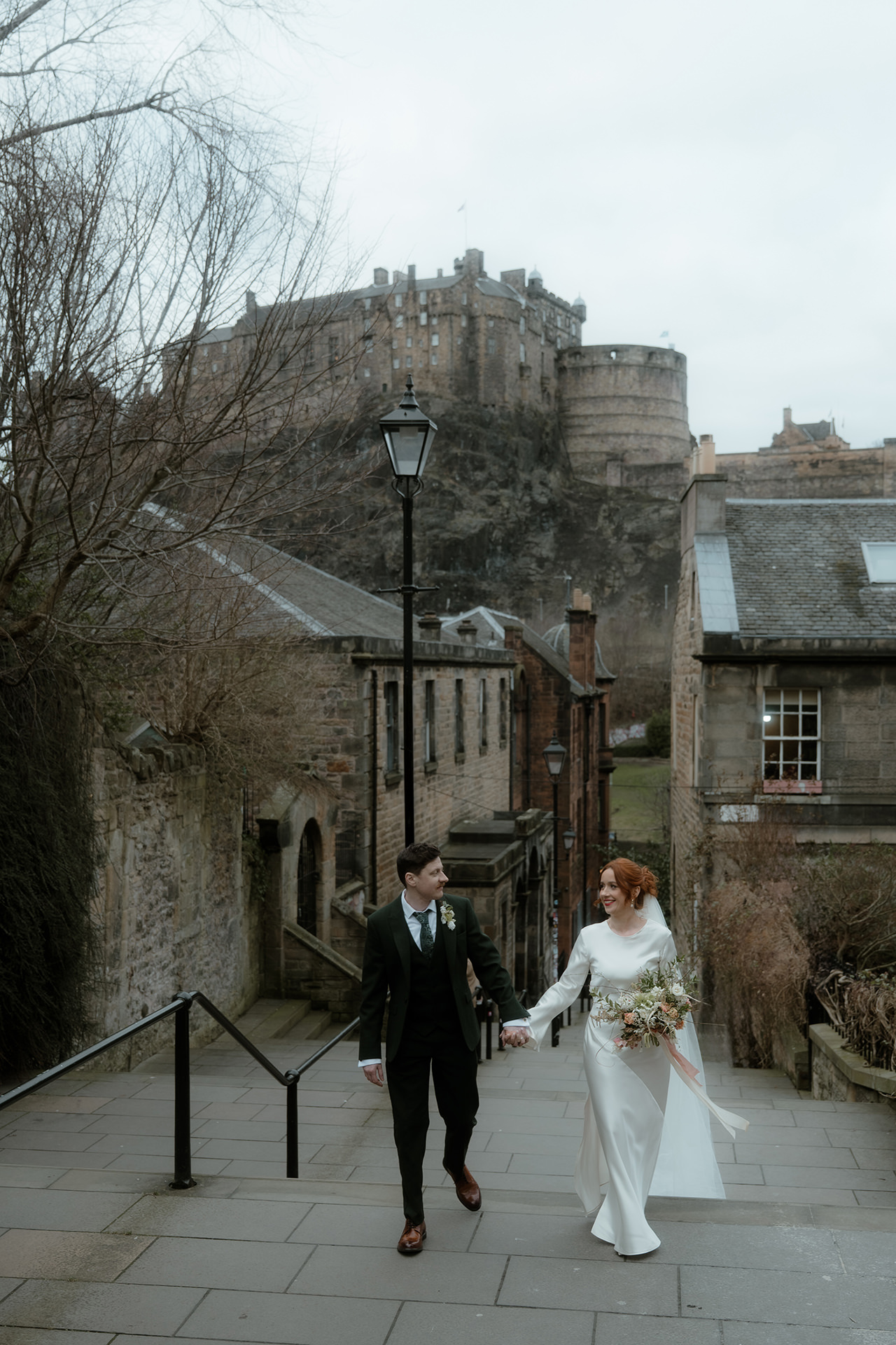 Bride and groom walking up the Vennel Steps with Edinburgh Castle in the background