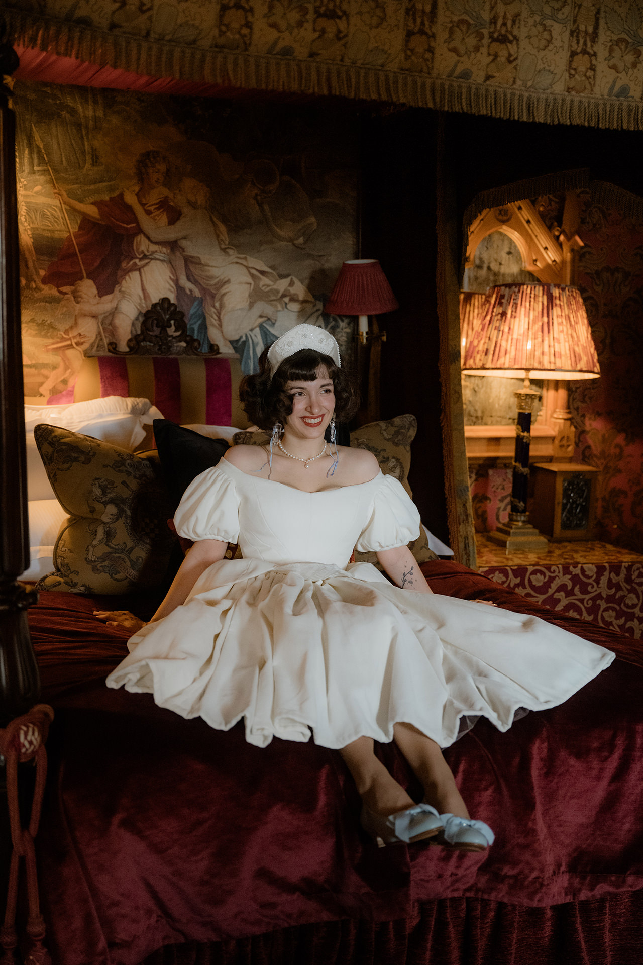 Bride sitting on the bed at the Witchery suite in Edinburgh with rich, draped decor of the bedroom surrounding her