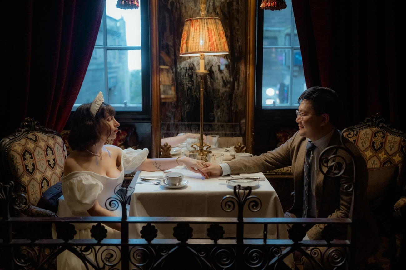 Newlyweds holding hands on the table in their Witchery wedding suite in Scotland