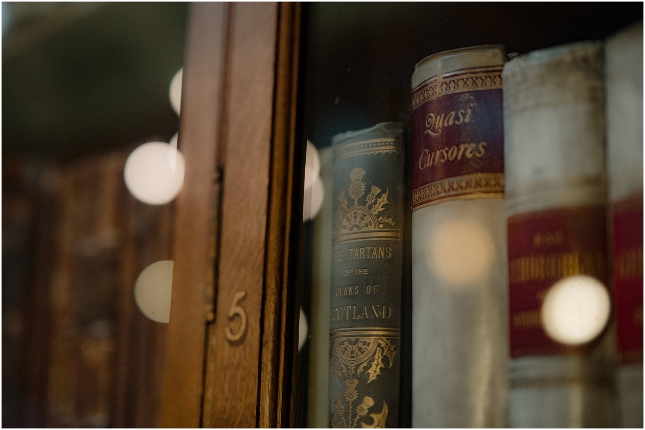 Close-up of antique books behind glass in the Royal College of Physicians library, including titles like “The Tartans of the Clans of Scotland.”