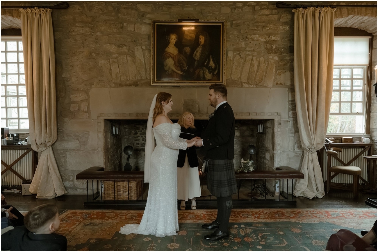Cosy & Intimate Wedding at Ferniehirst Castle in the Scottish Borders 9 Intimate wedding ceremony inside Ferniehirst Castle with the couple exchanging vows by the fireplace