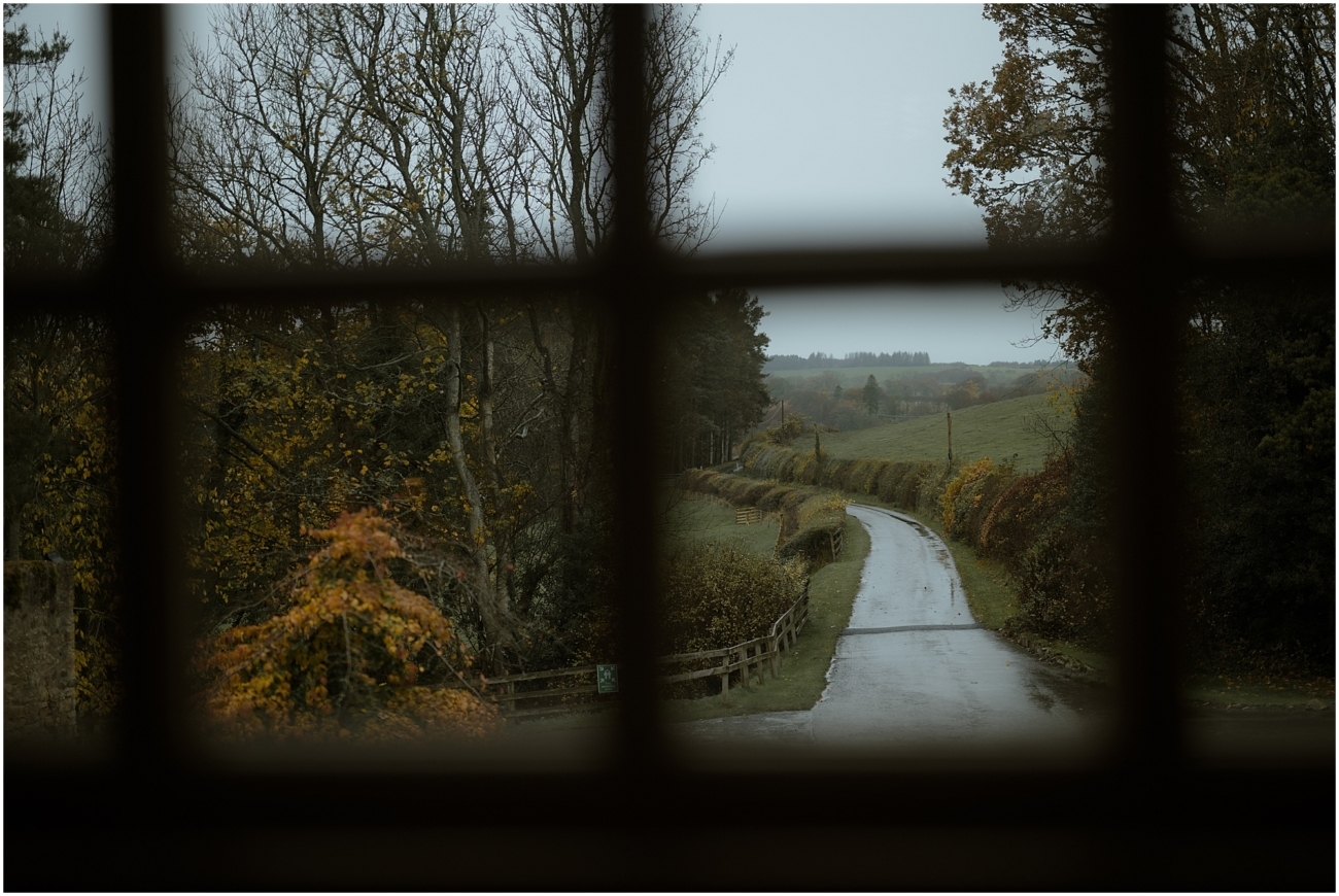 Cosy & Intimate Wedding at Ferniehirst Castle in the Scottish Borders 29 View of a country road and autumn landscape through a castle window in the Scottish Borders
