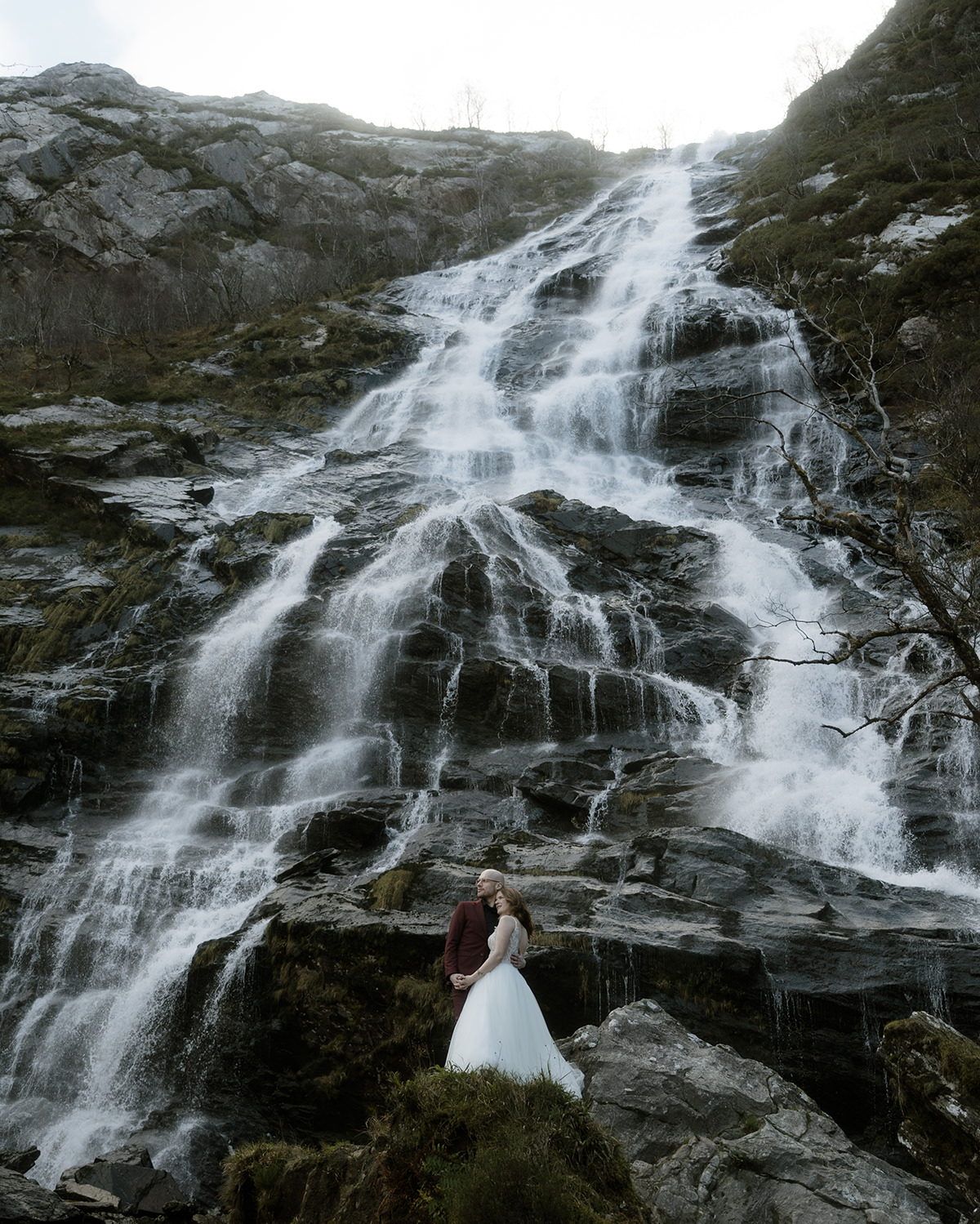 Bride and groom standing at the bottom of the majestic Steall Falls in Glen Nevis