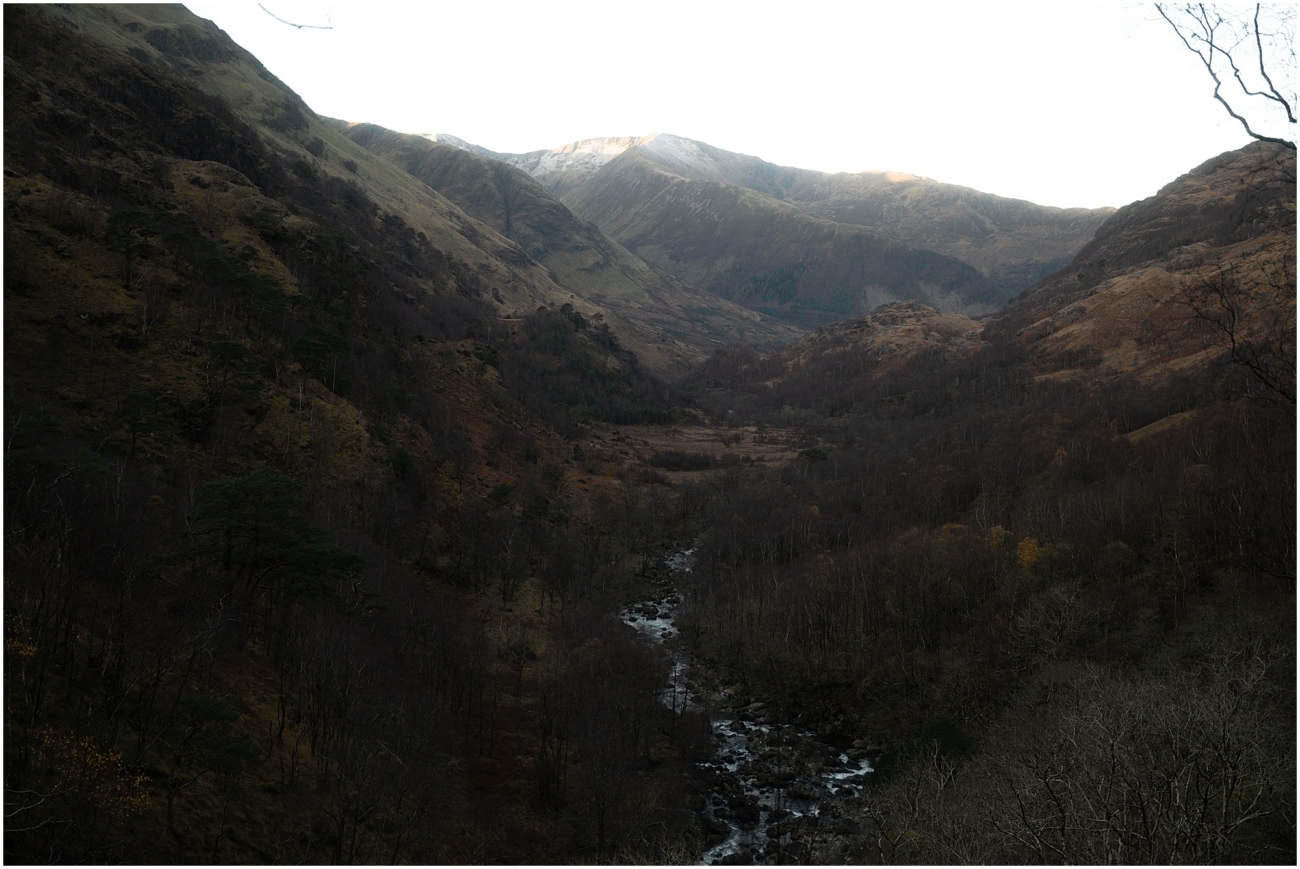 Steall Falls elopement in Glen Nevis 1 Scenic view of Glen Nevis valley in the Scottish Highlands with a river winding through bare winter trees and snow-kissed mountain peaks