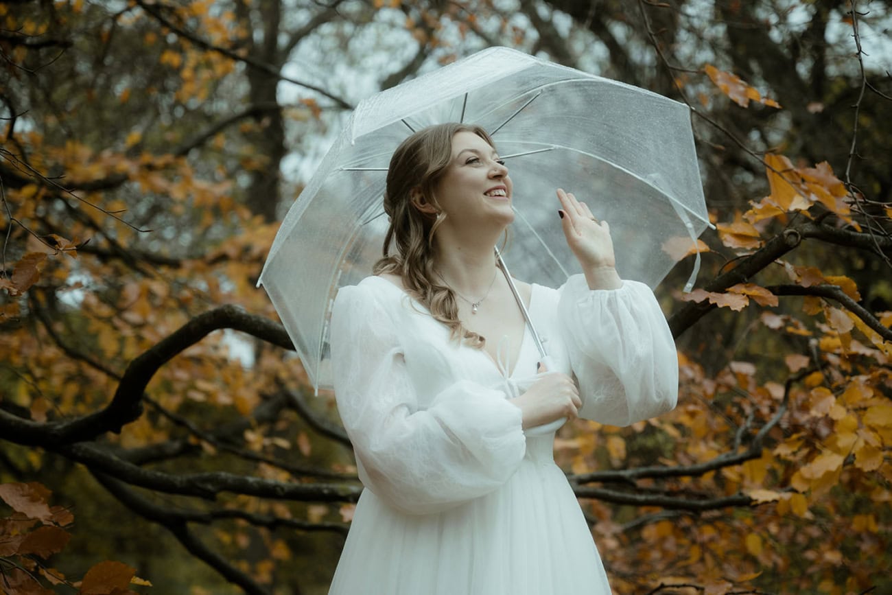 Weddings at the Royal College of Physicians Edinburgh: everything you need to know 7 Bride laughing under a clear umbrella surrounded by autumn foliage in Queen Street Gardens Edinburgh