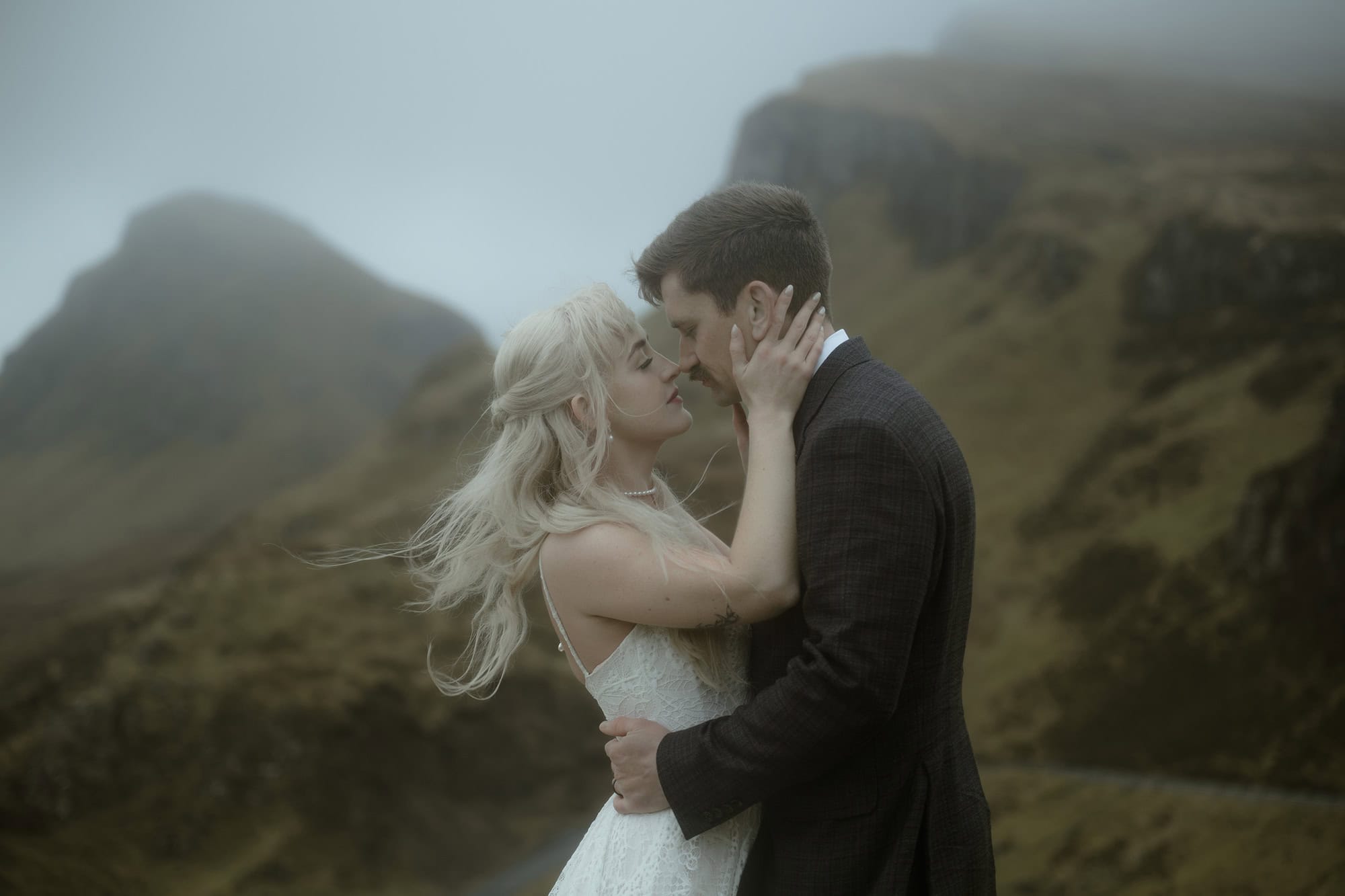 Bride and groom sharing an intimate moment at the Quiraing on the Isle of Skye, moody fog rolling over the mountains behind them