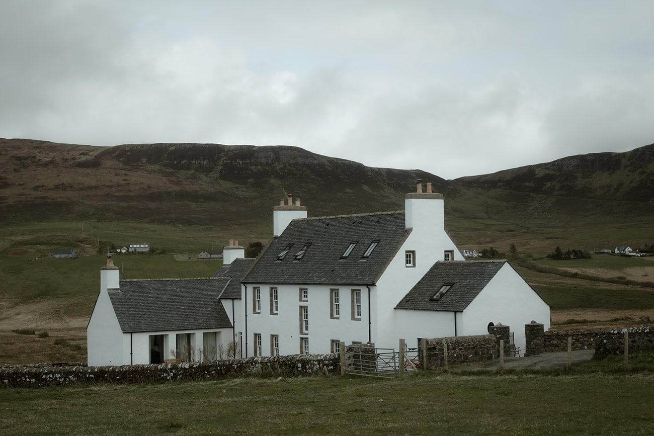 Monkstadt Hotel on the Isle of Skye - a whitewashed historic country house set against overcast Highland hills, perfect as a elopement getting-ready venue