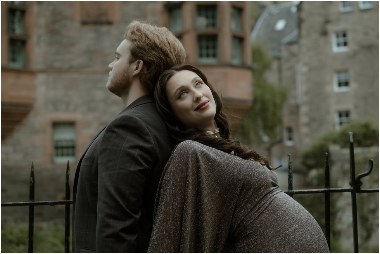 Woman leaning back against her partner looking up dreamily with Well Court building behind in Dean Village Edinburgh