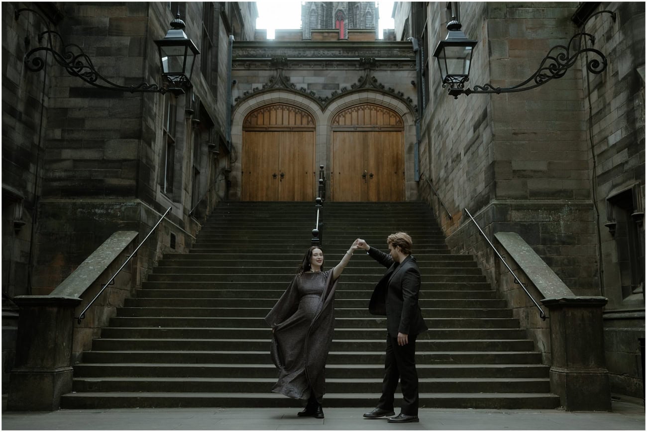 Couple dancing and twirling in front of a grand symmetrical gothic staircase on the Royal Mile Edinburgh
