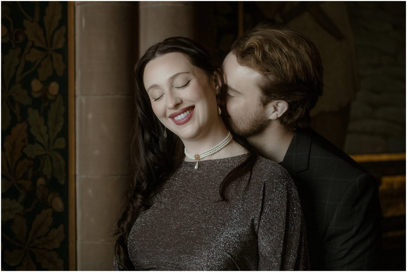 Close-up of woman smiling with eyes closed wearing a pearl choker as partner kisses her cheek in the Scottish National Portrait Gallery