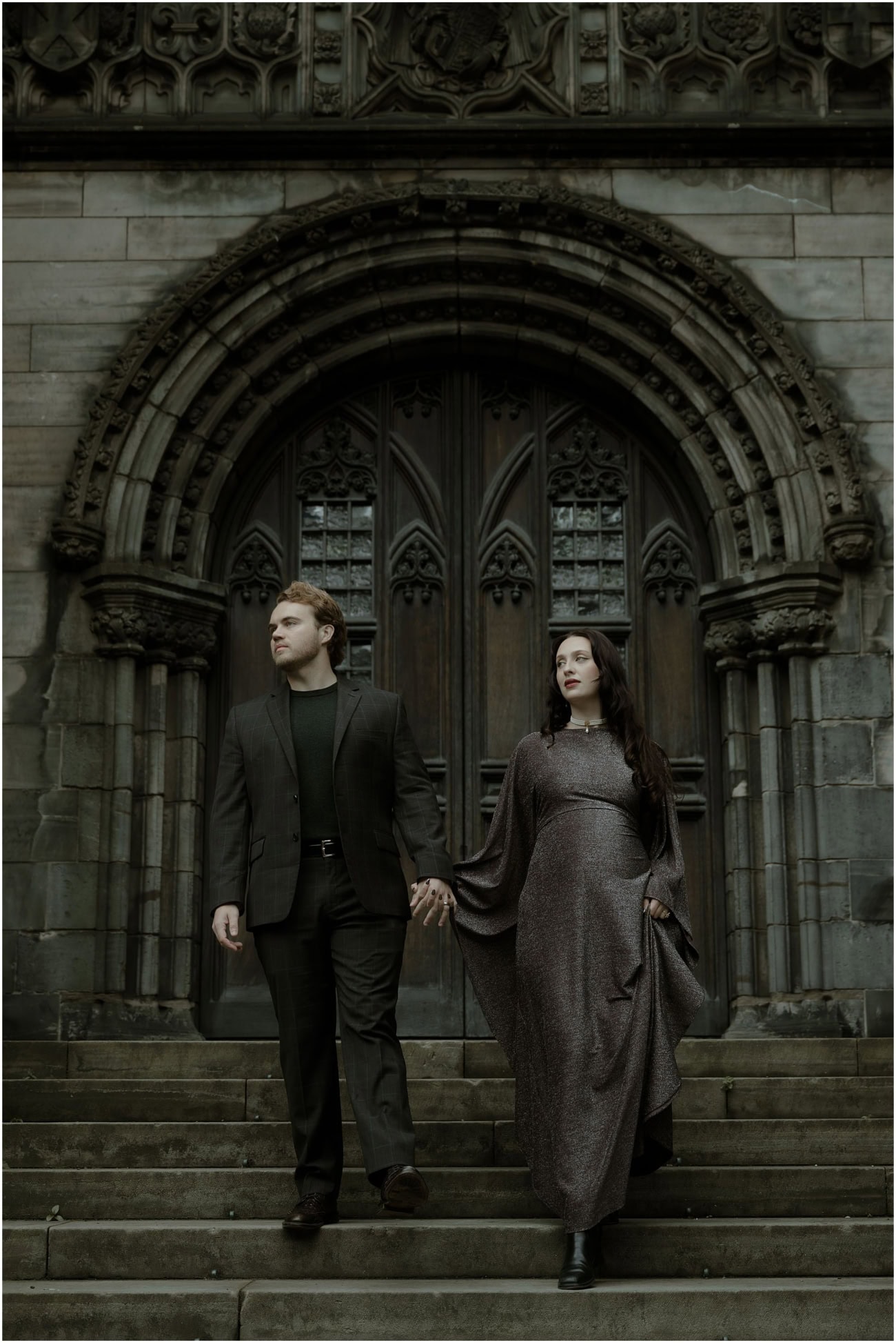 Couple holding hands on the steps of St Giles Cathedral Edinburgh during a dark academia gothic couples session