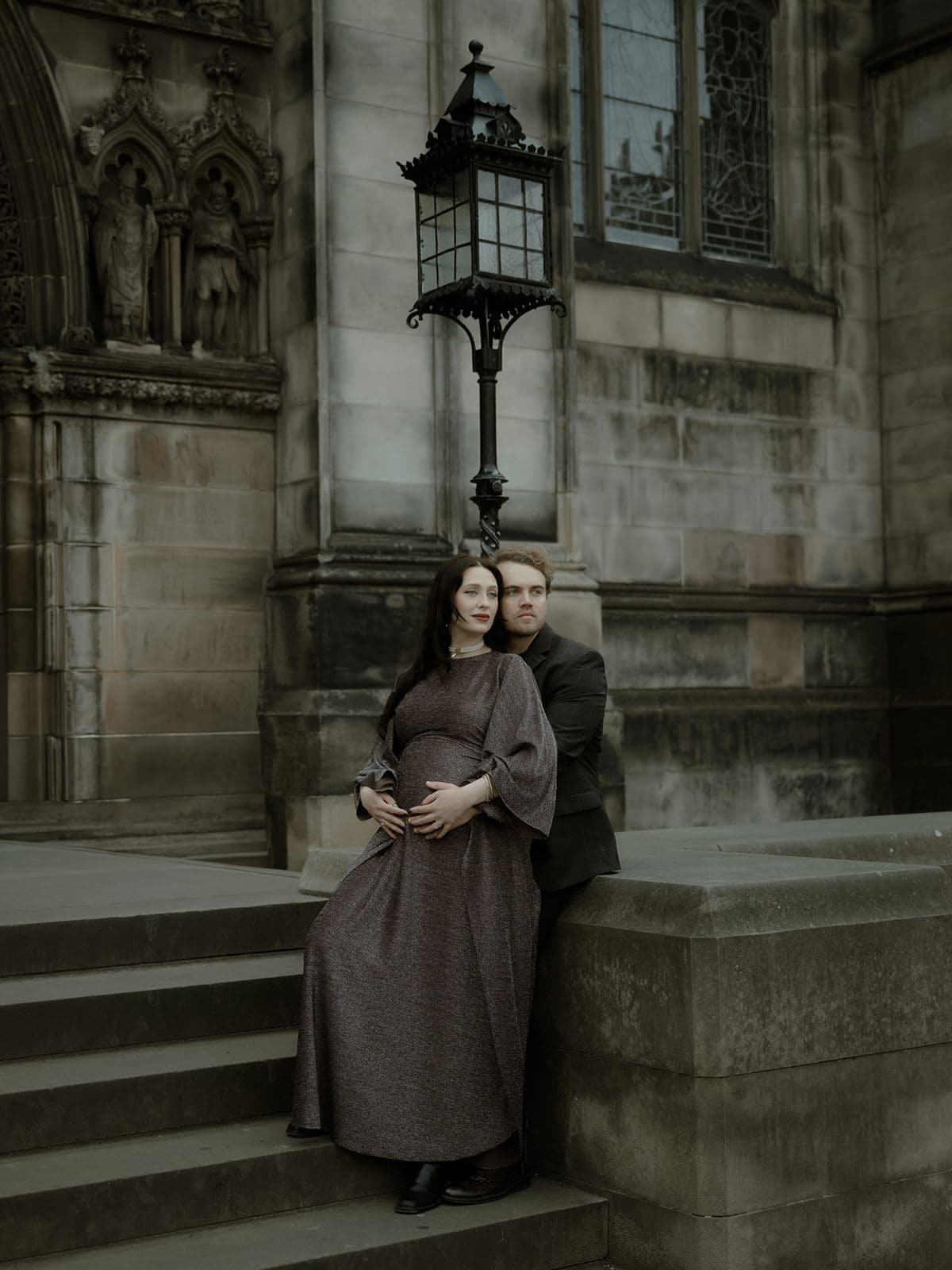 Bride and groom embracing beside a Victorian iron lamppost of St Giles Cathedral against gothic stone architecture in Edinburgh