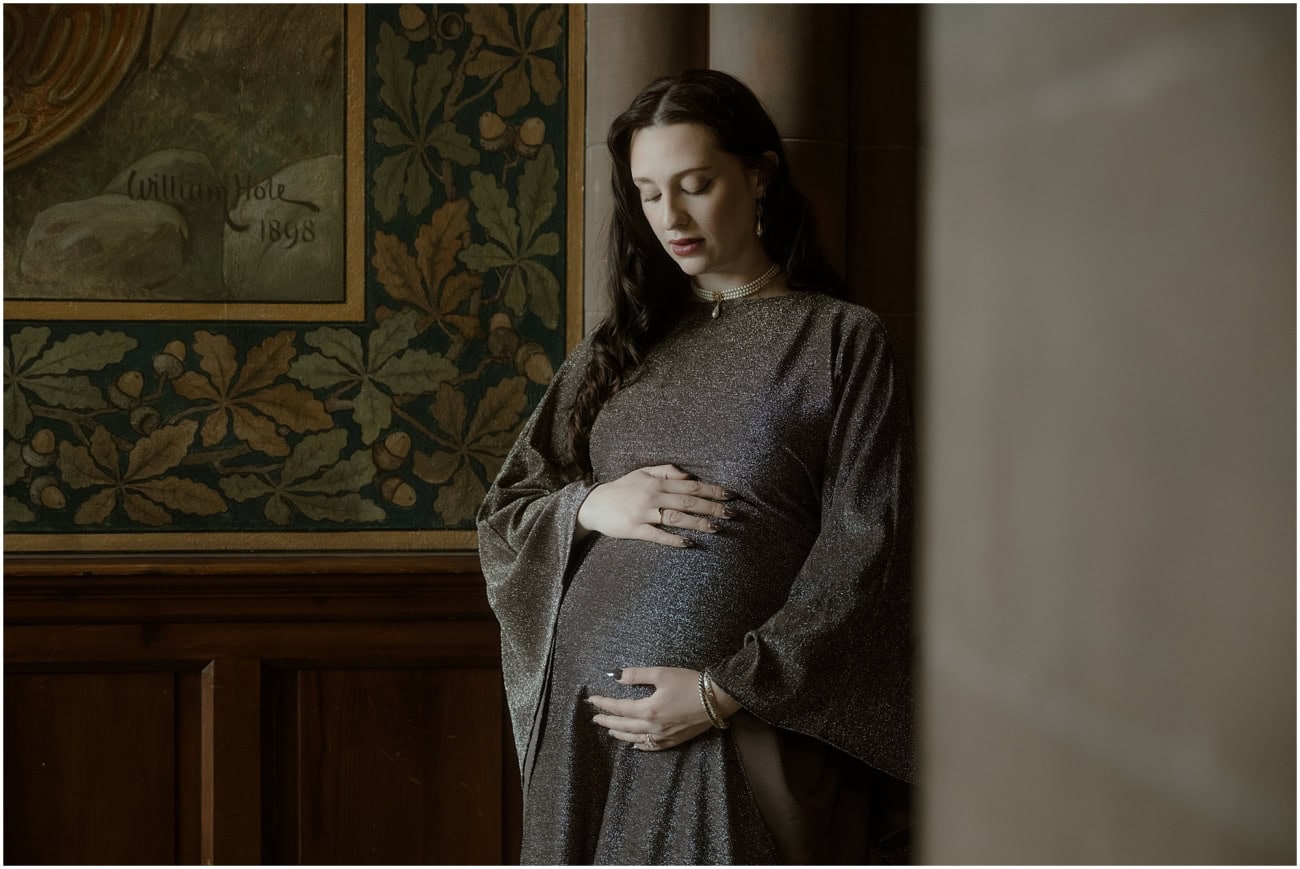 Pregnant woman in profile holding her bump beneath the Mission of St Columba mural in the Scottish National Portrait Gallery Edinburgh