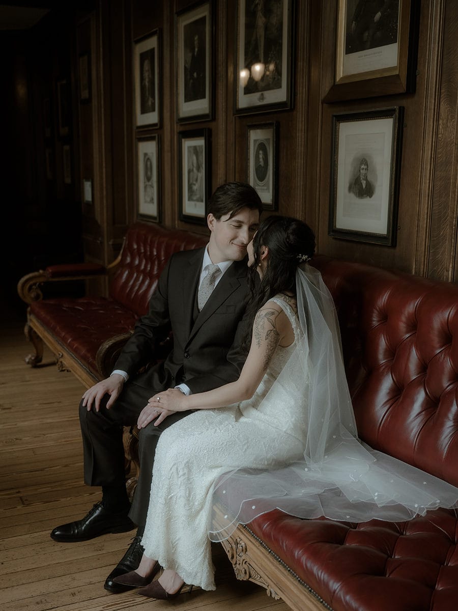 Weddings at the Royal College of Physicians Edinburgh: everything you need to know 10 Bride and groom sitting together on a red leather sofa in the corridor at the Royal College of Physicians Edinburgh